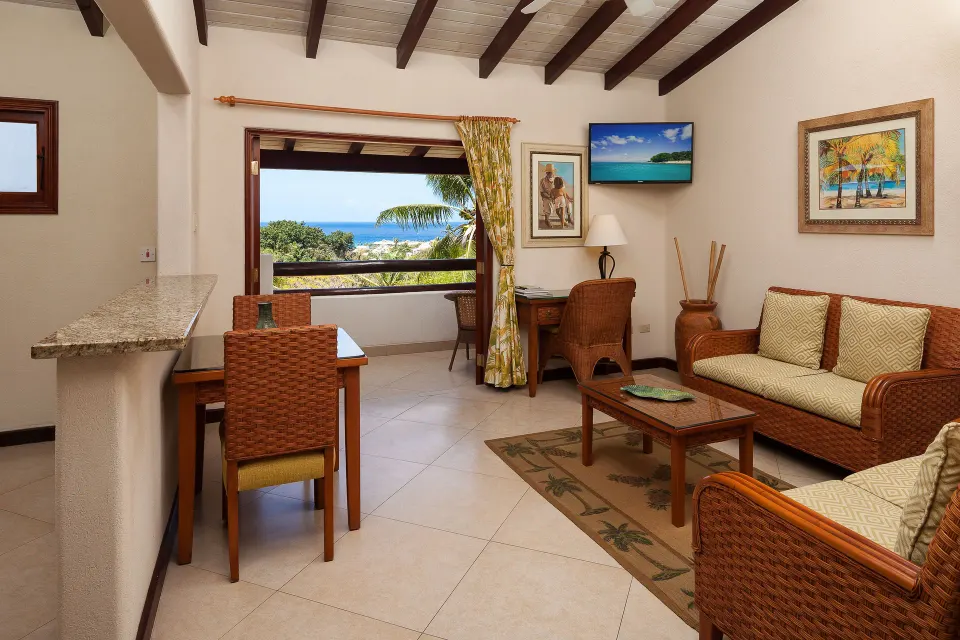 Suite living area with wicker seating and ocean-facing balcony at Sugar Cane Club Hotel And Spa.