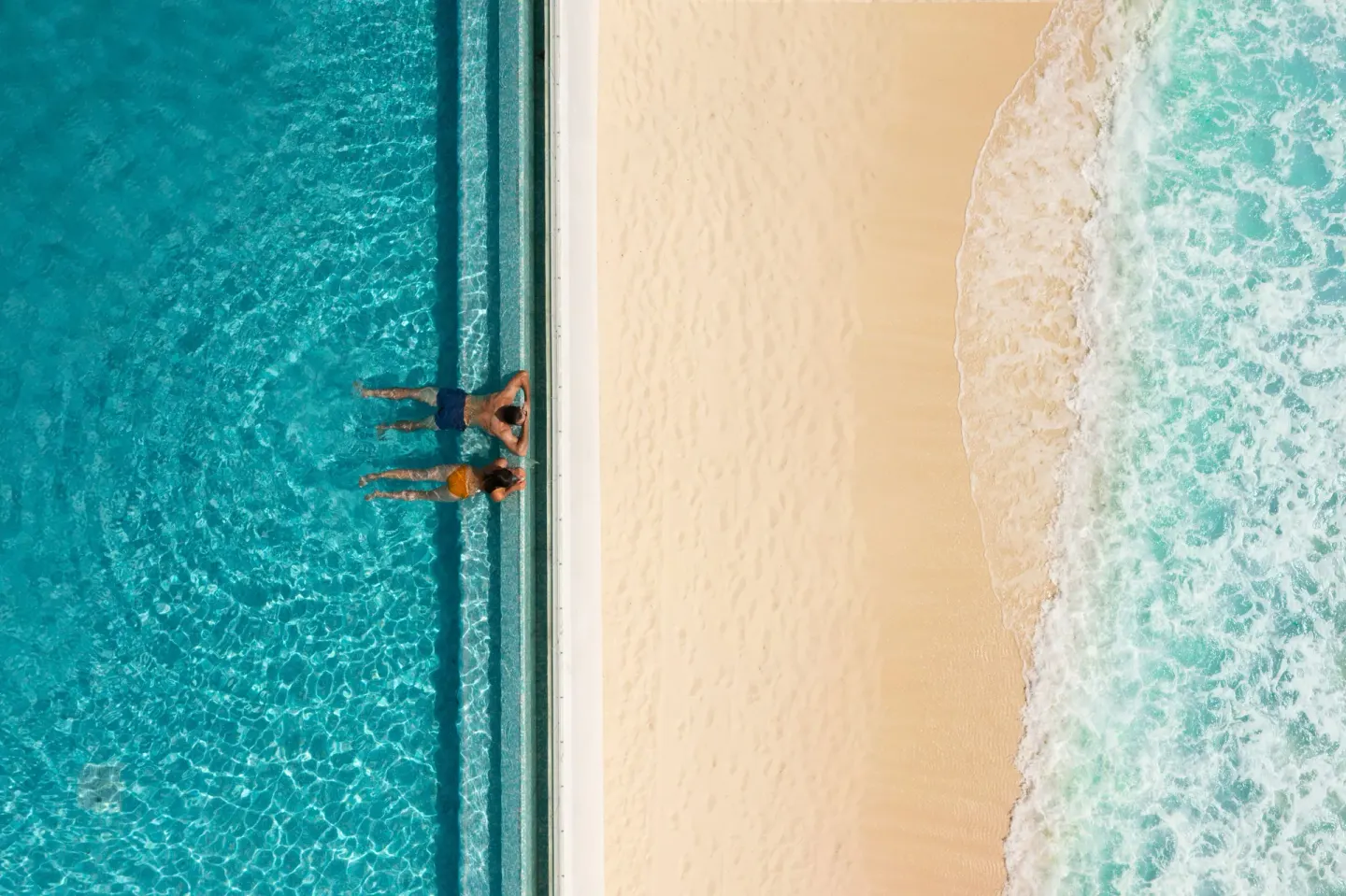 An aerial view shows two guests in the pool beside the beach at Sun Palace Cancun.