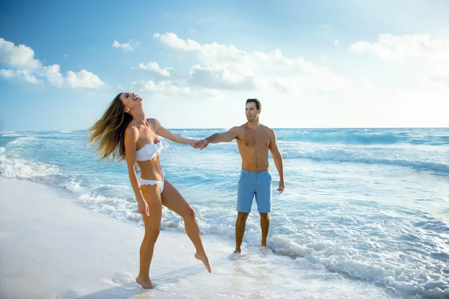 Couple holding hands in the surf on the beach at Sun Palace Cancun.