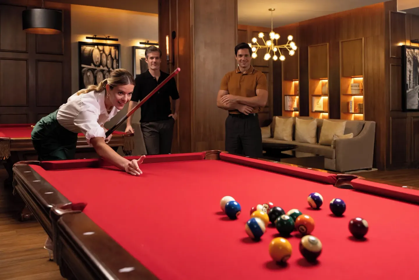 Guests playing billiards on a red pool table in a lounge at Sun Palace Cancun.