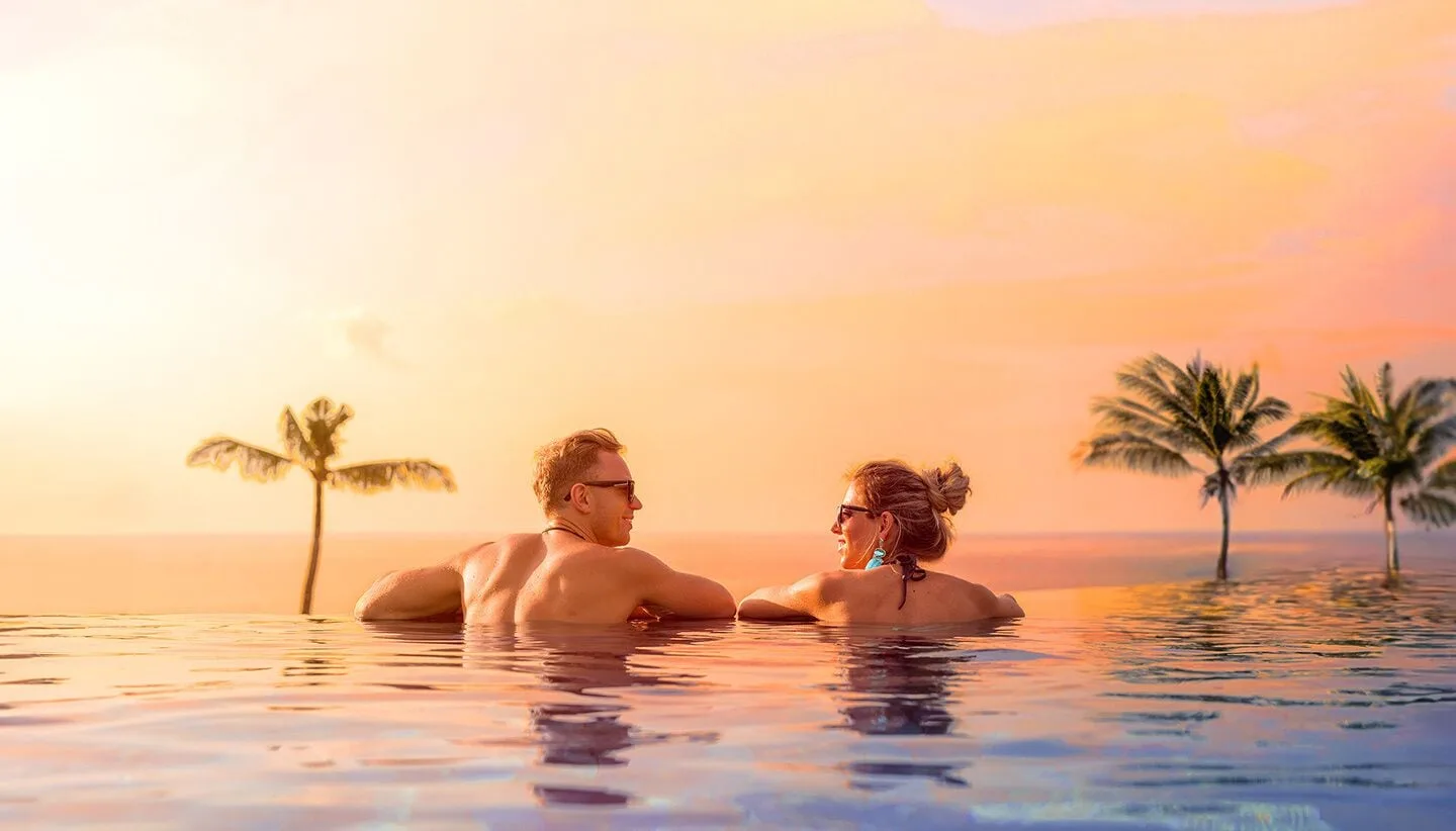 Couple relaxing in an infinity pool at sunset at Sun Palace Cancun.