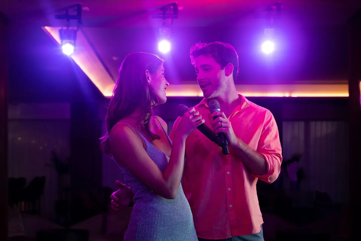 Two guests sing into microphones under purple lights at Sun Palace Cancun.