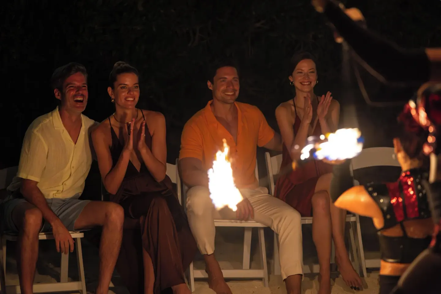 Guests watching a nighttime fire performance on the beach at Sun Palace Cancun.