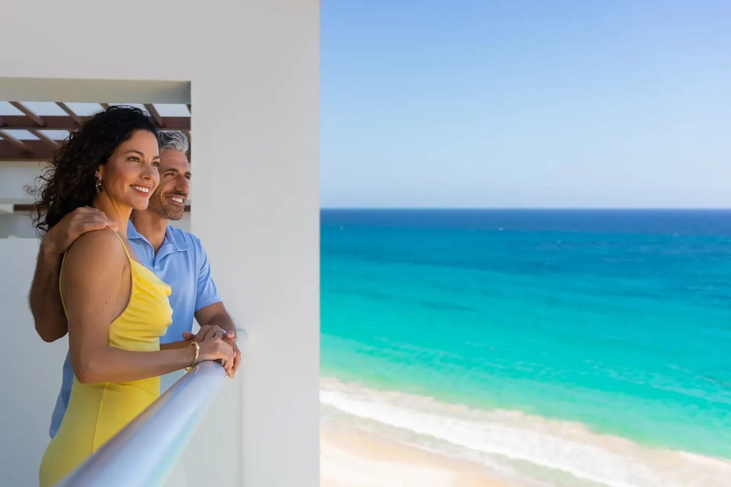 Couple standing on a balcony overlooking turquoise ocean at Sun Palace Cancun.