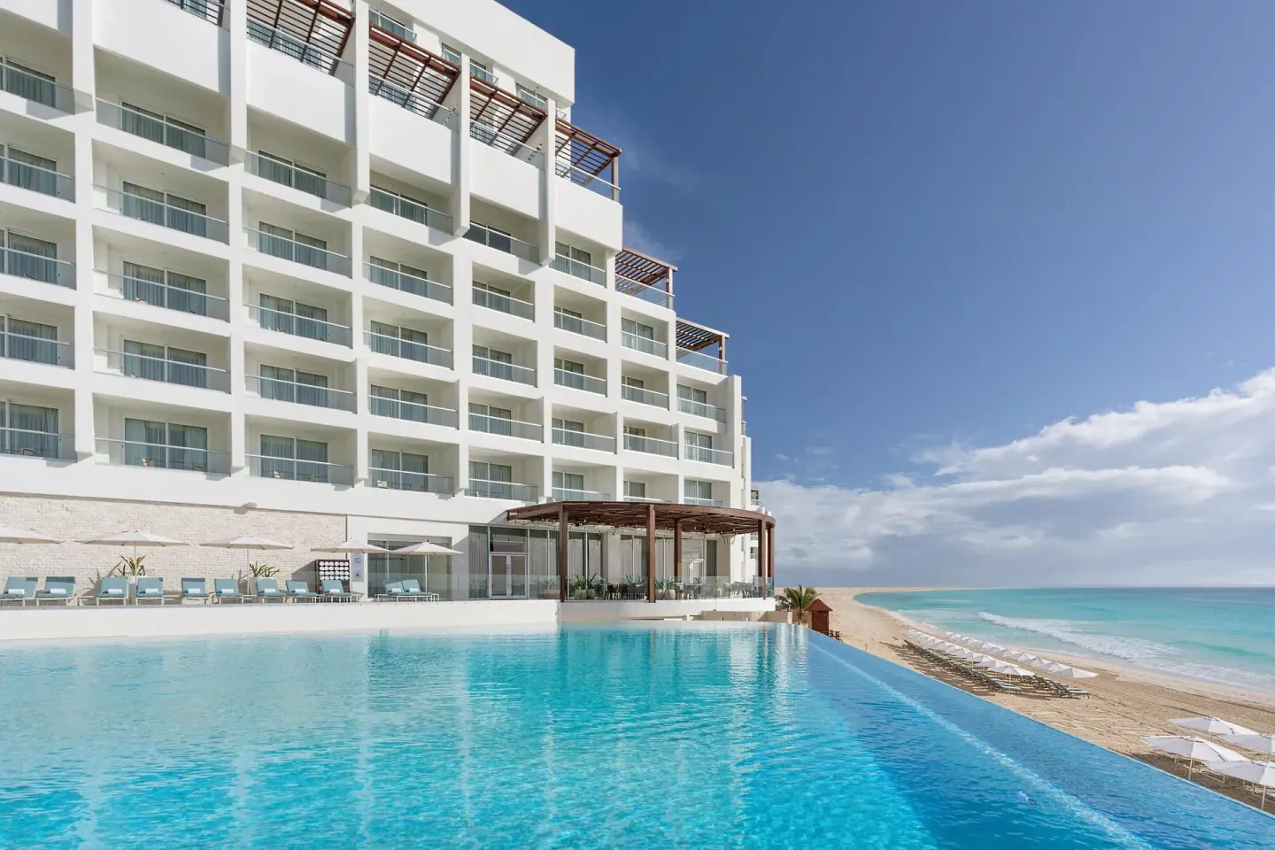 The oceanfront resort building and infinity pool overlook the beach at Sun Palace Cancun.
