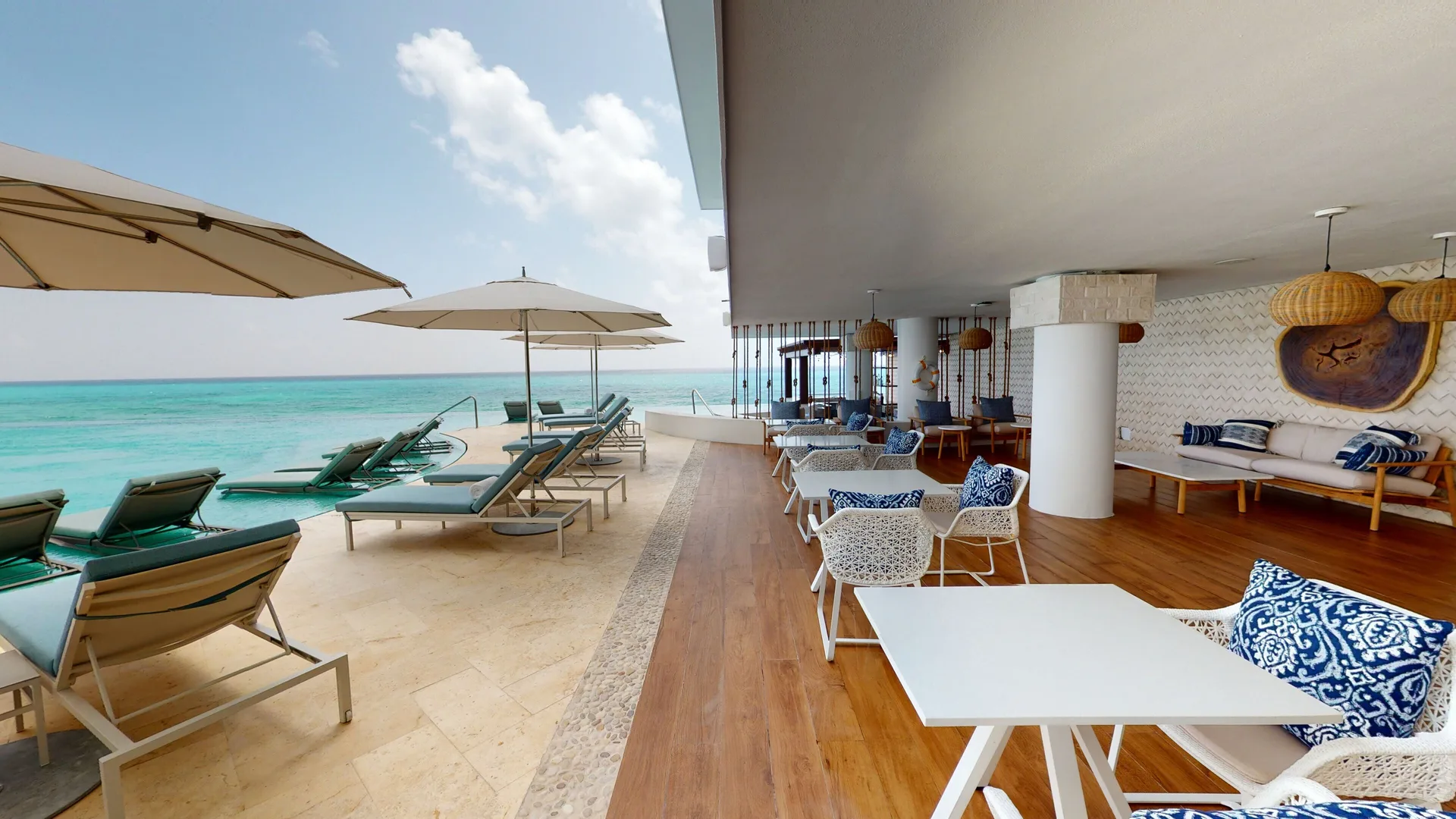 An oceanfront terrace with lounge seating and umbrellas at Sun Palace Cancun.