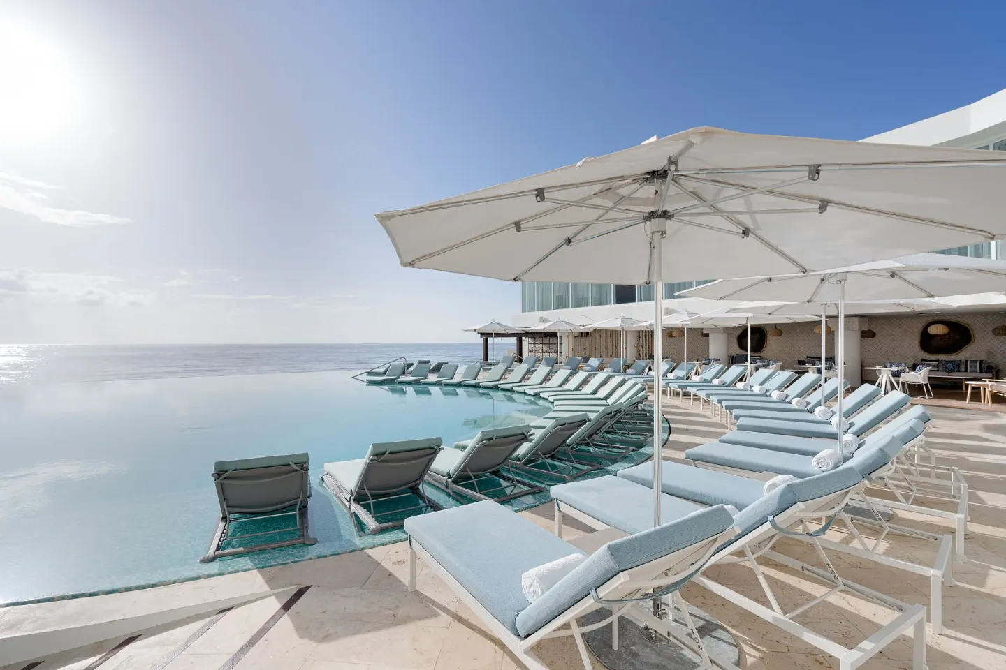 Rows of shaded pool loungers face the ocean at Sun Palace Cancun.