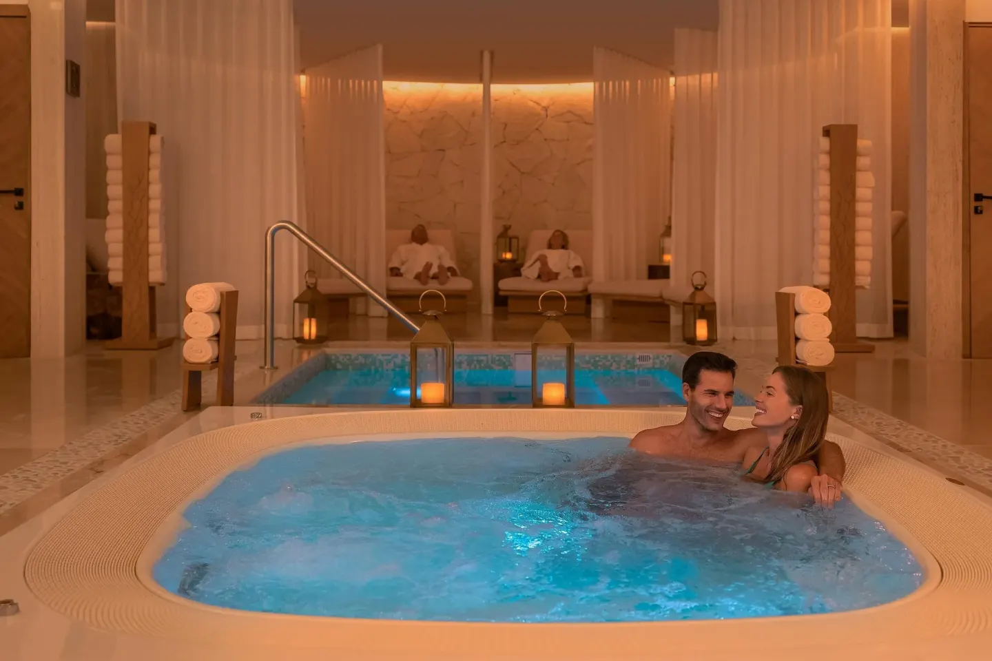 Couple relaxing in a spa whirlpool with lanterns and loungers at Sun Palace Cancun.