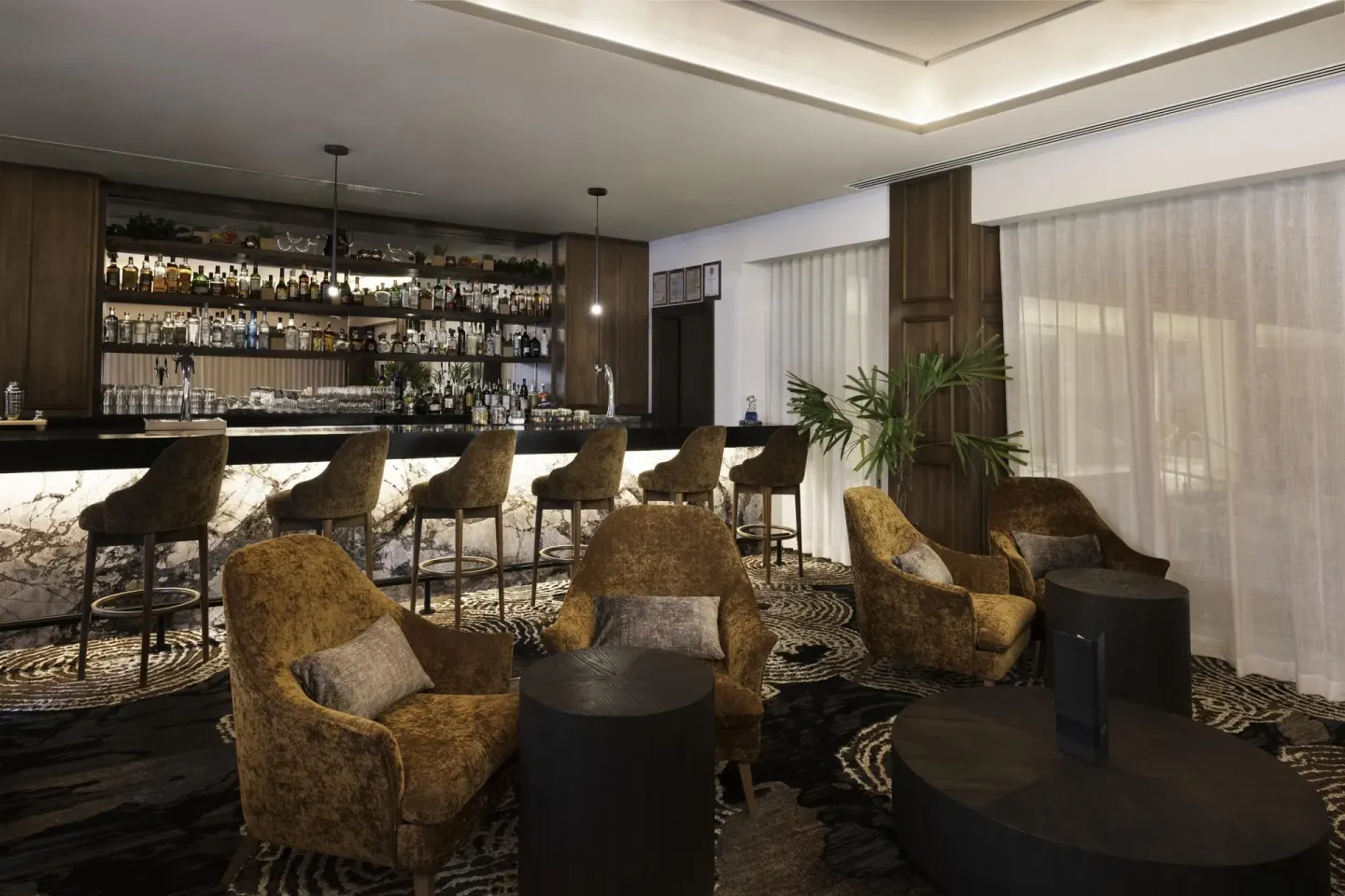 A lounge bar with counter seating and armchairs is shown at Sun Palace Cancun.