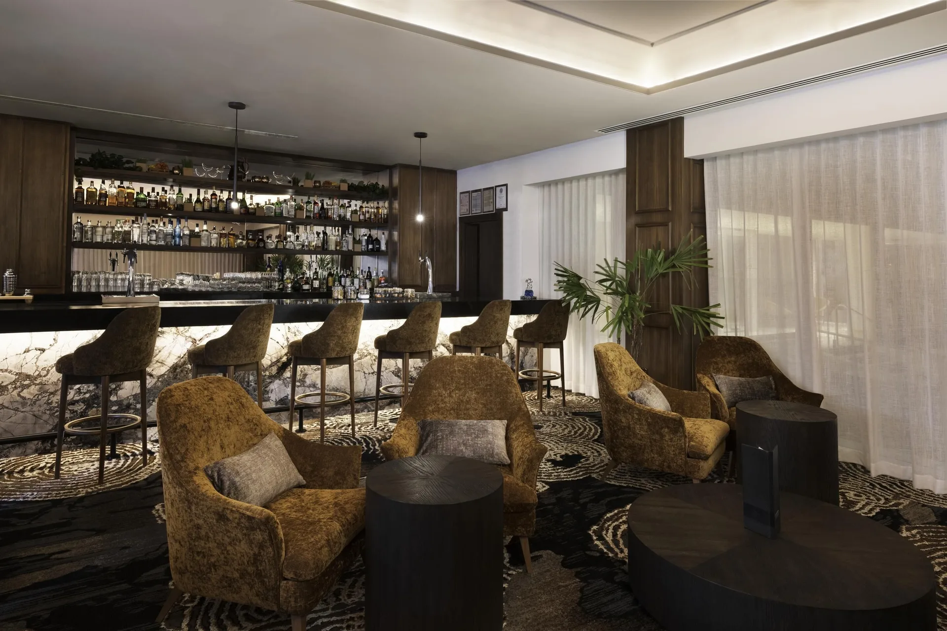 A lounge bar with counter seating and armchairs is shown at Sun Palace Cancun.