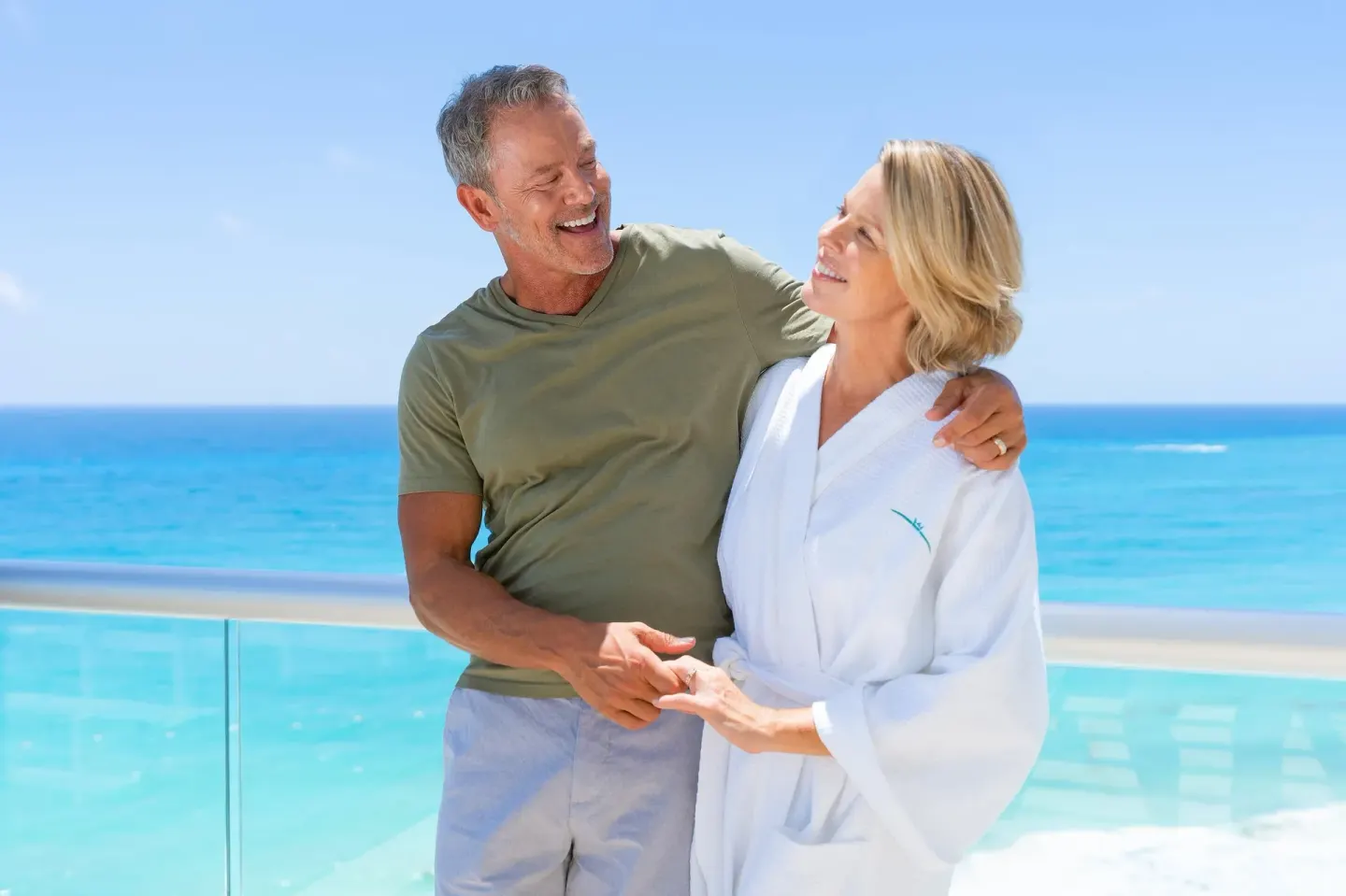 Couple on the ocean-view balcony of a Superior Deluxe room at Sun Palace Cancun.
