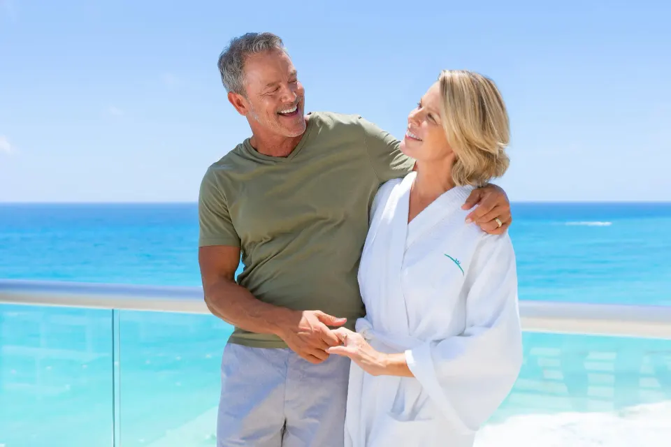Couple on the ocean-view balcony of a Superior Deluxe room at Sun Palace Cancun.