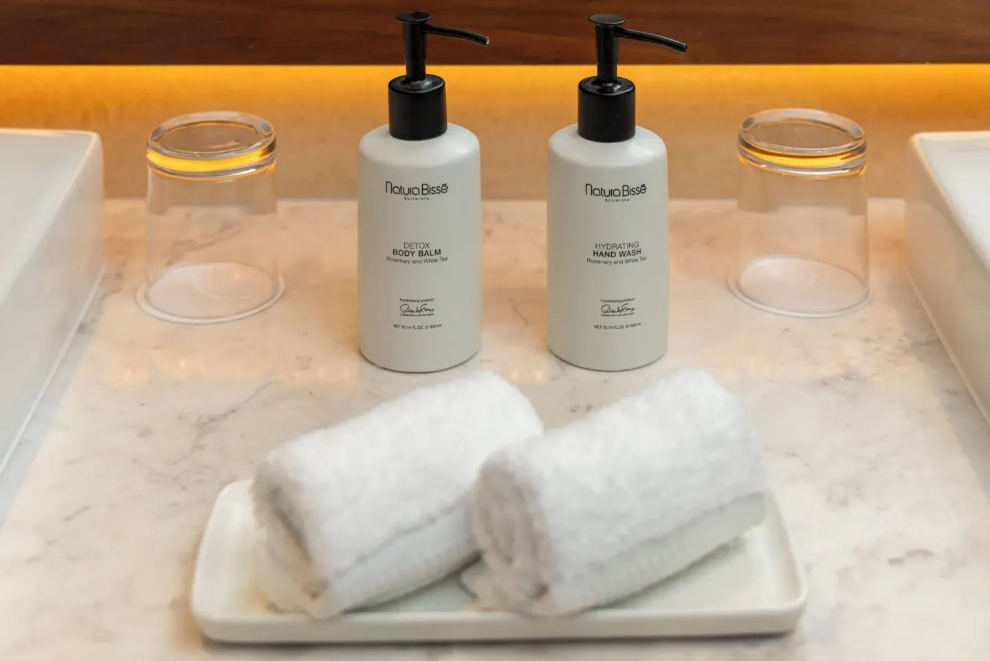Bathroom counter with pump amenities, glasses, and rolled towels at Sun Palace Cancun.