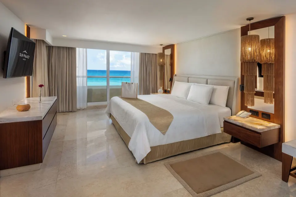 Superior Governor Suite king bed with ocean-facing balcony doors at Sun Palace Cancun.