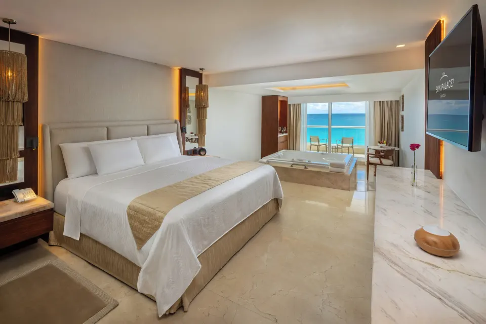 Superior Junior Suite Ocean View king bed with tub, TV, and ocean-facing balcony at Sun Palace Cancun.