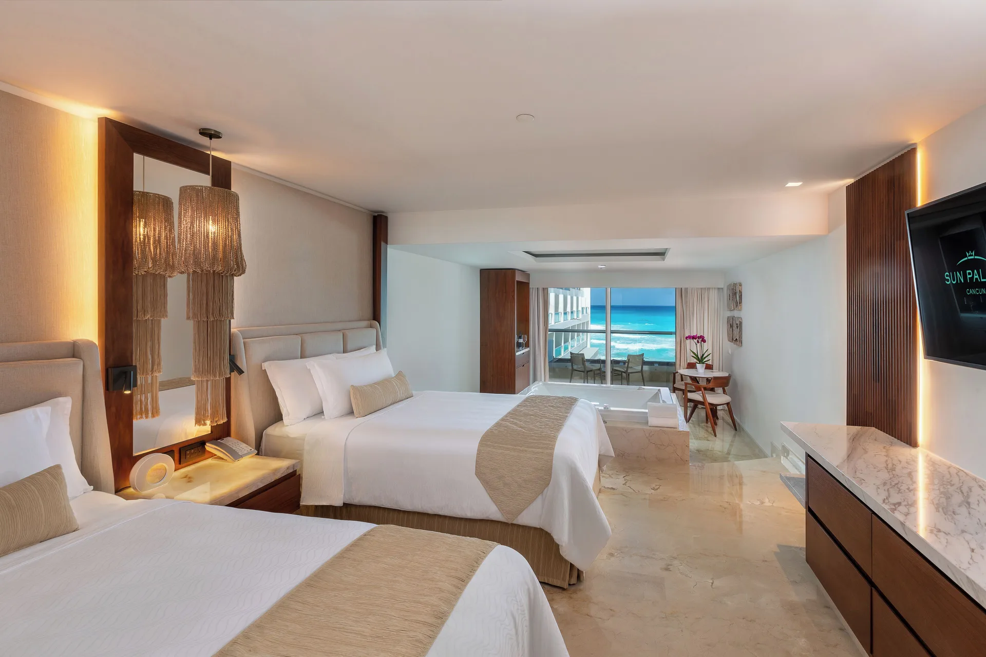 Superior Junior Suite Ocean View with two beds, seating area, and balcony view at Sun Palace Cancun.
