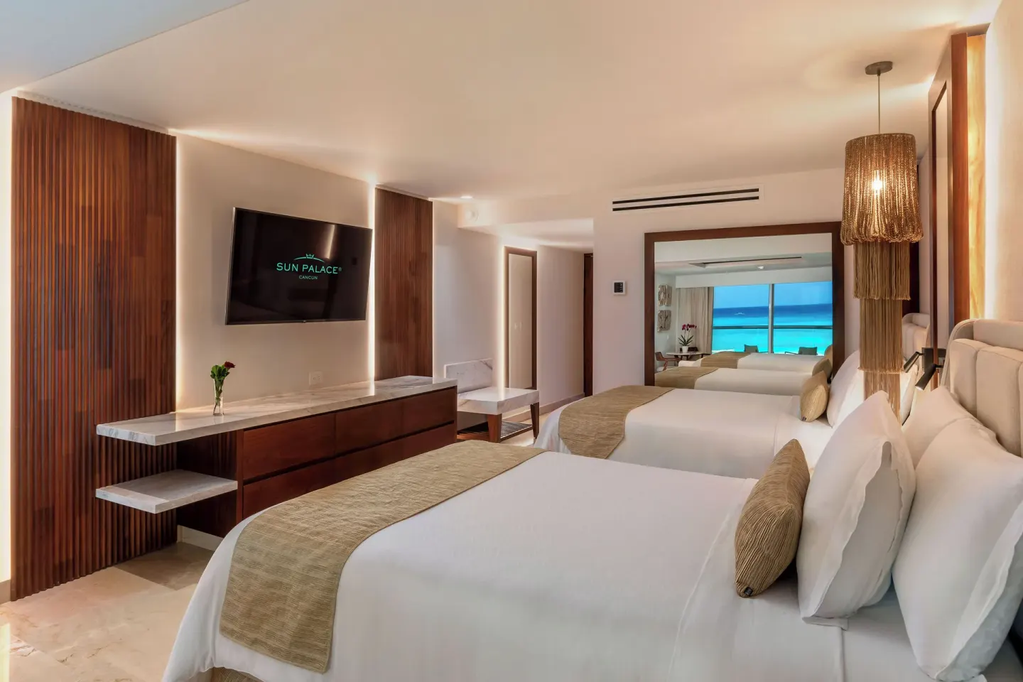 Superior Junior Suite Ocean View with two beds and turquoise sea beyond at Sun Palace Cancun.