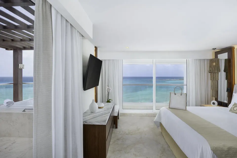 Ocean-view bedroom with king bed and balcony tub in a presidential suite at Sun Palace Cancun.