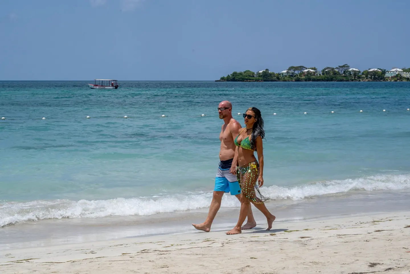 A couple walks along the waterline on the beach at Sunset at the Palms Resort.