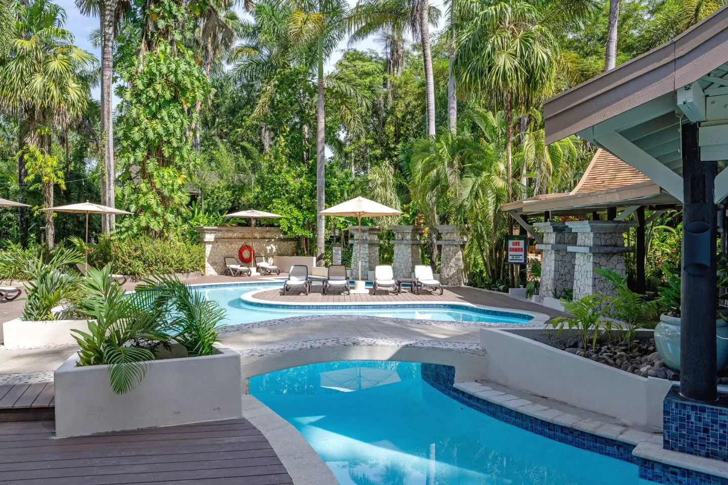 Curved pool, deck, and loungers among palms at Sunset at the Palms Resort.