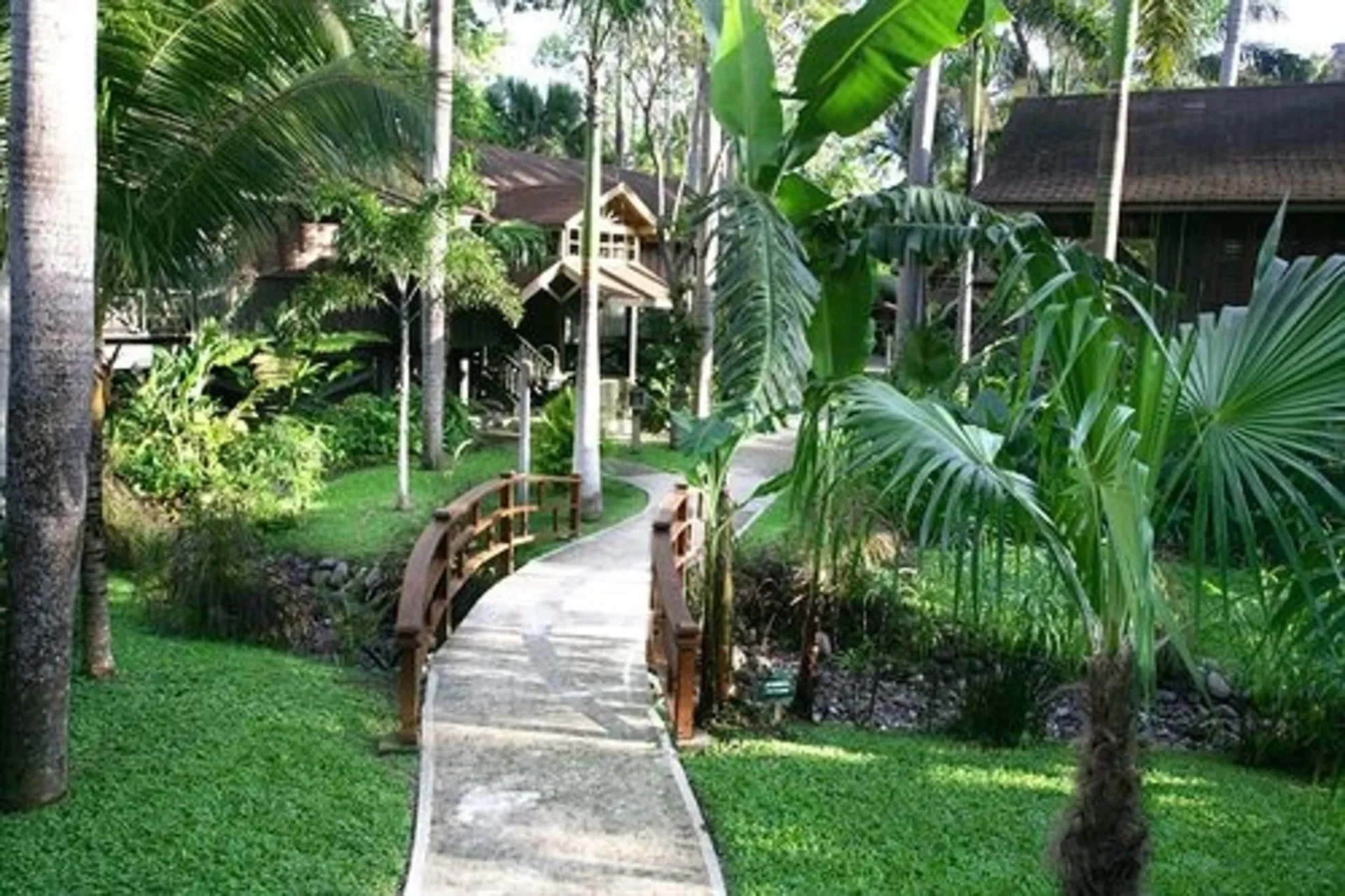 Curving walkway over a wooden bridge through gardens at Sunset at the Palms Resort.