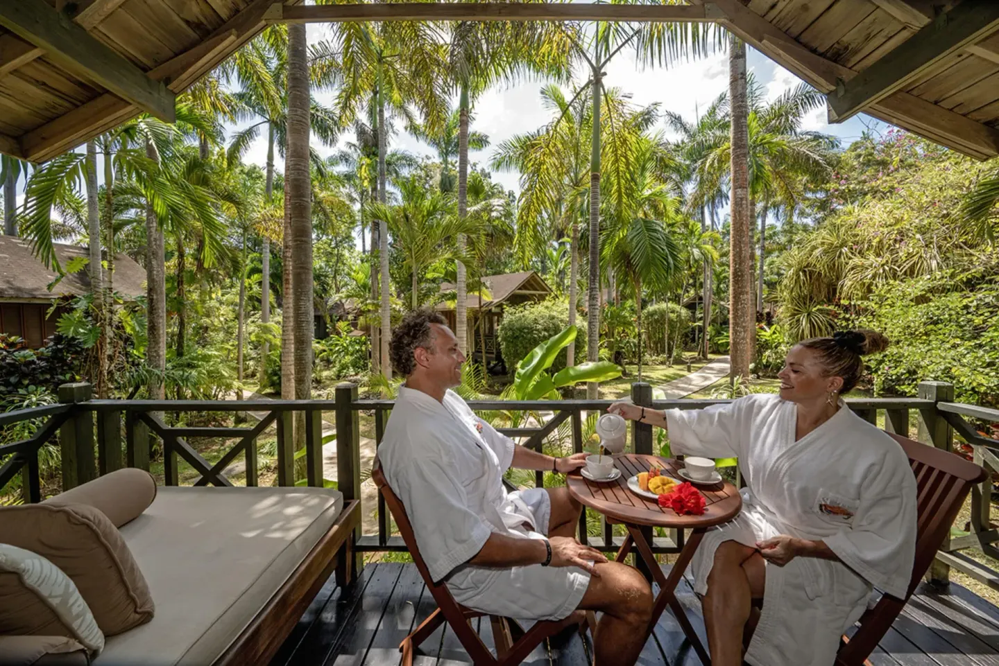 Guests in robes having drinks on a garden balcony at Sunset at the Palms Resort.