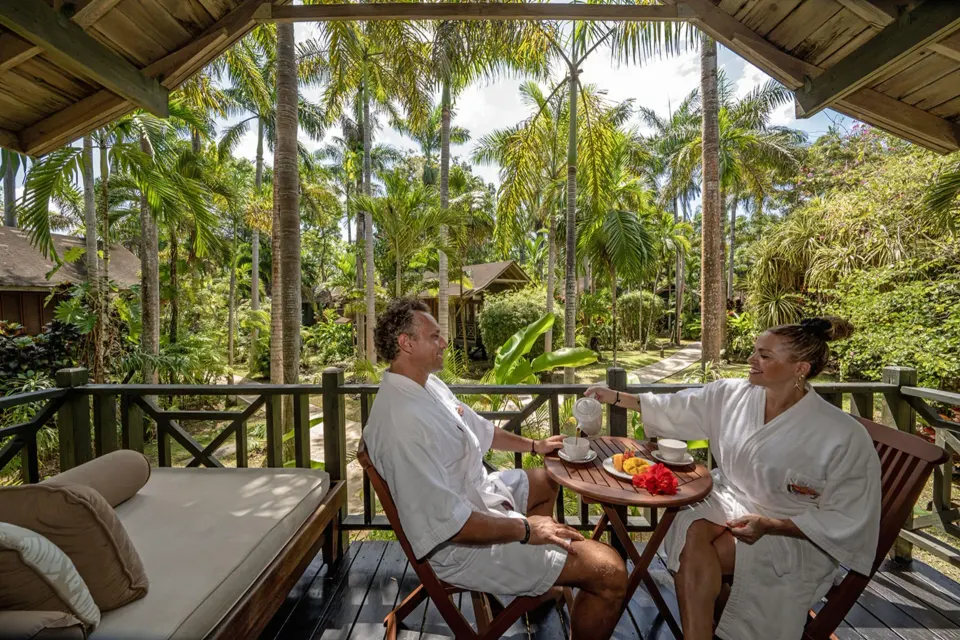Guests in robes having drinks on a garden balcony at Sunset at the Palms Resort.