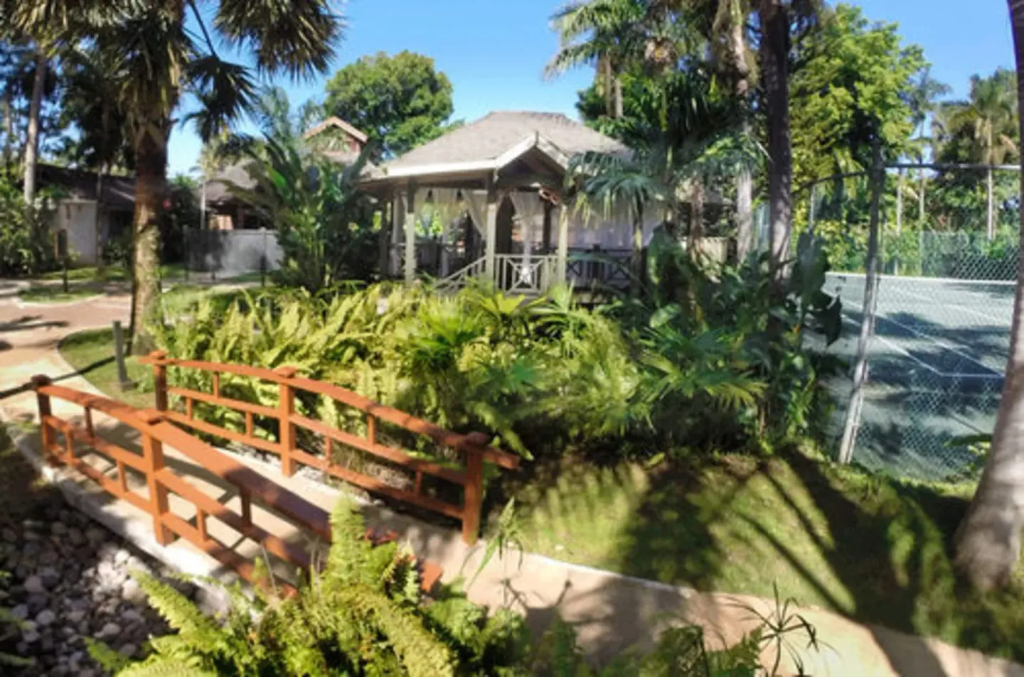 Garden bridge, gazebo, and tennis court at Sunset at the Palms Resort.