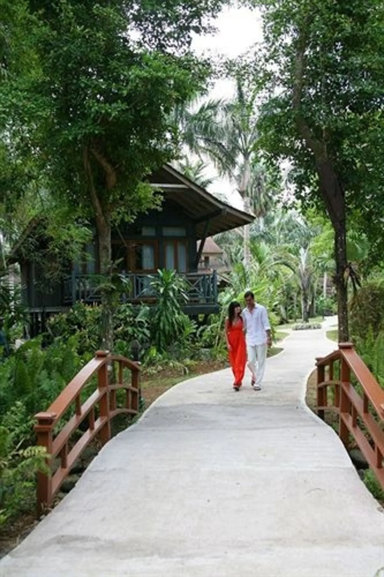 Guests walk a curved garden path by a treehouse-style building at Sunset at the Palms Resort.