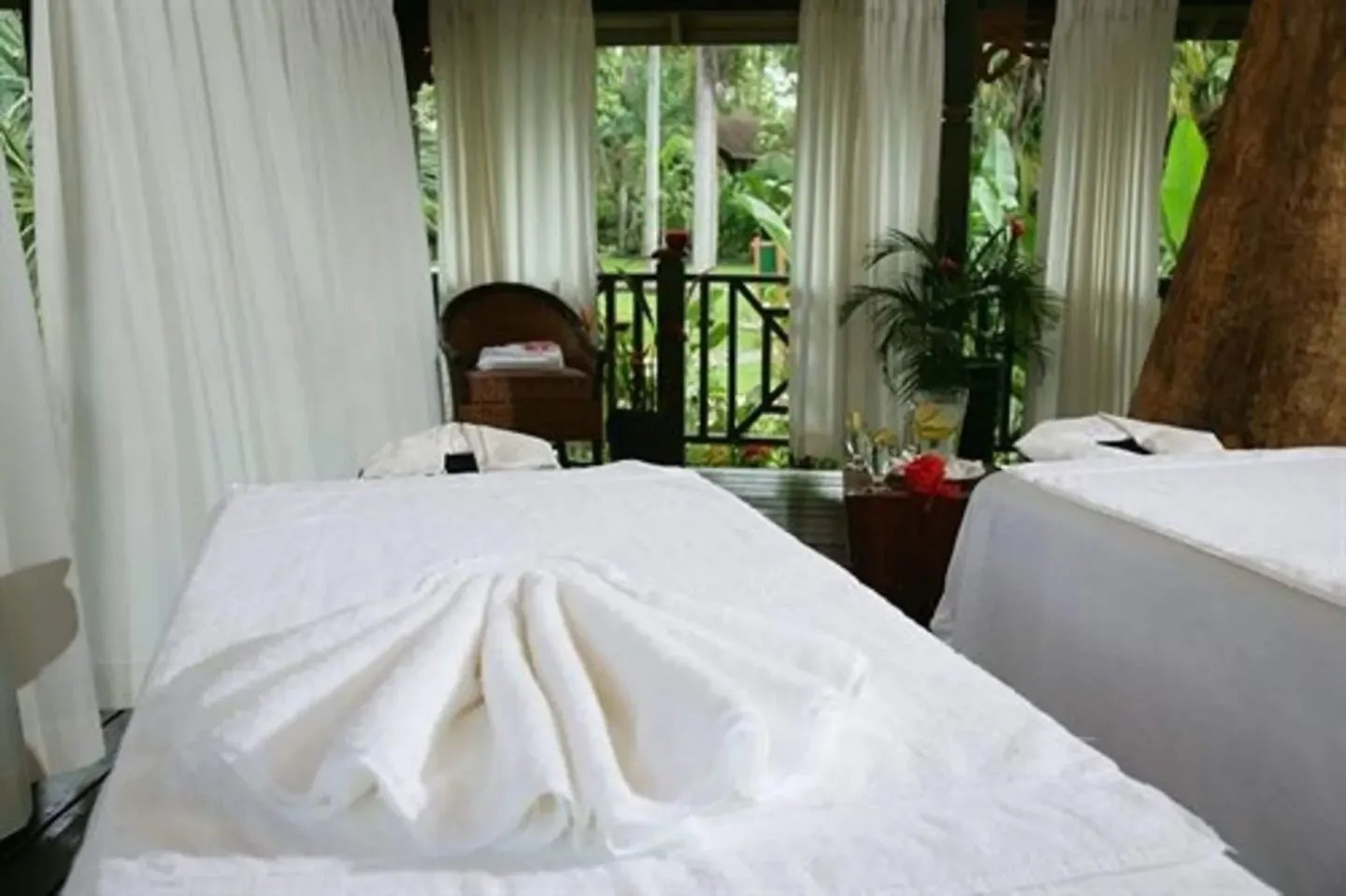 Two spa treatment beds beside garden curtains at Sunset at the Palms Resort.
