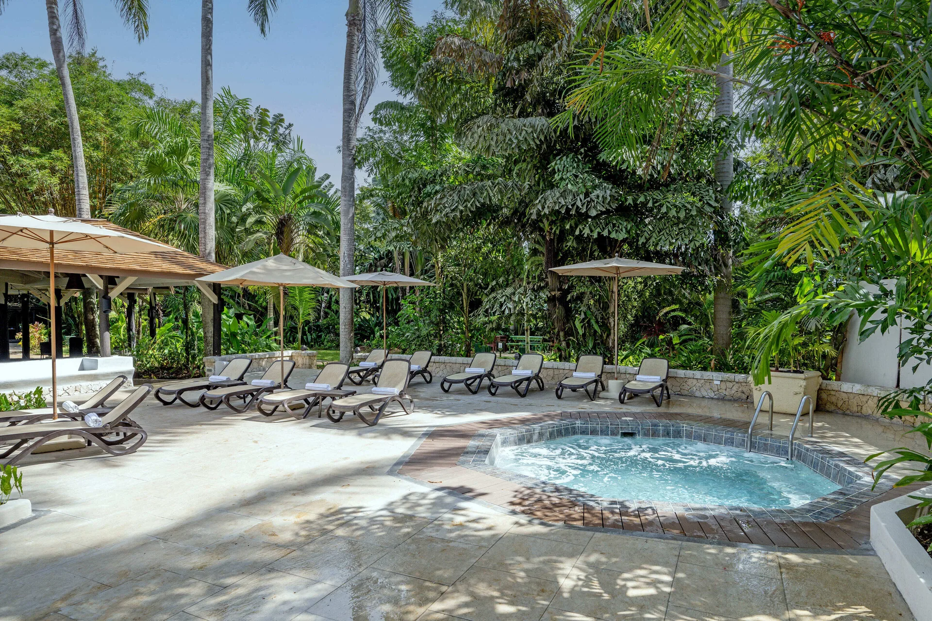 Round whirlpool and pool deck loungers in the garden at Sunset at the Palms Resort.