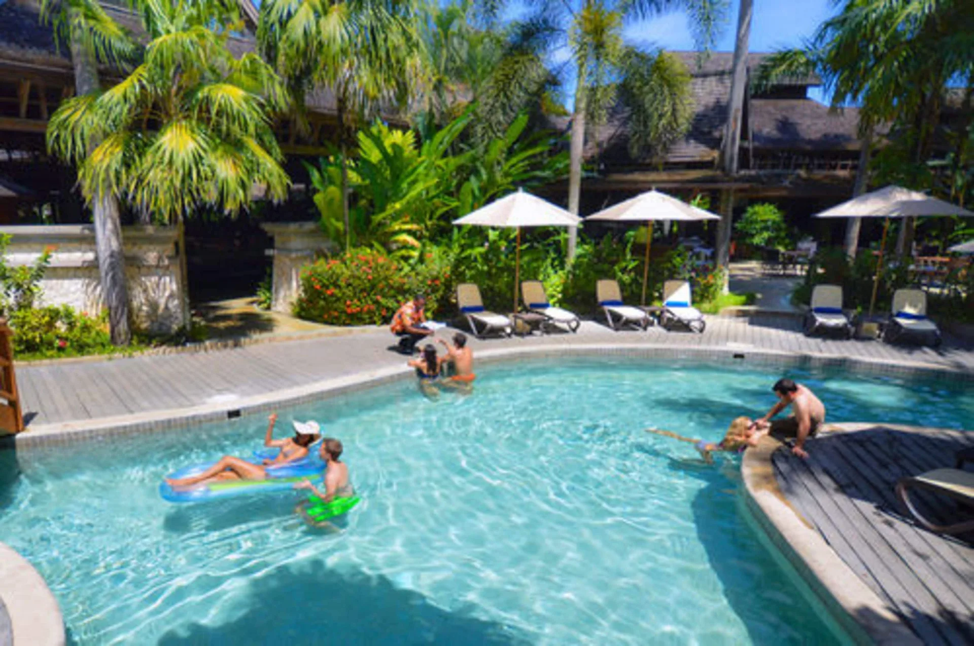 Guests swimming and floating in the resort pool at Sunset at the Palms Resort.