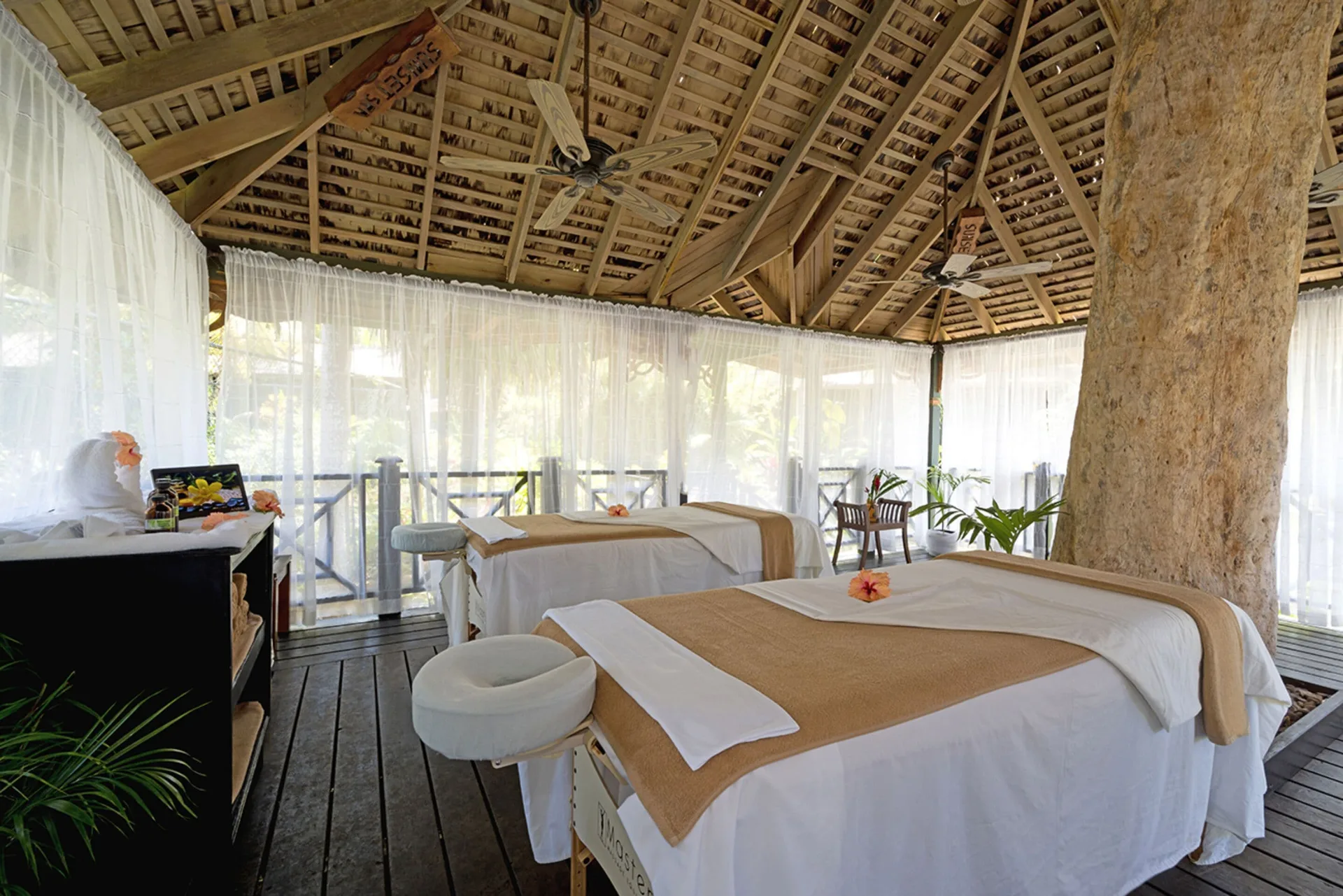 Open-air spa treatment room with two massage tables at Sunset at the Palms Resort.