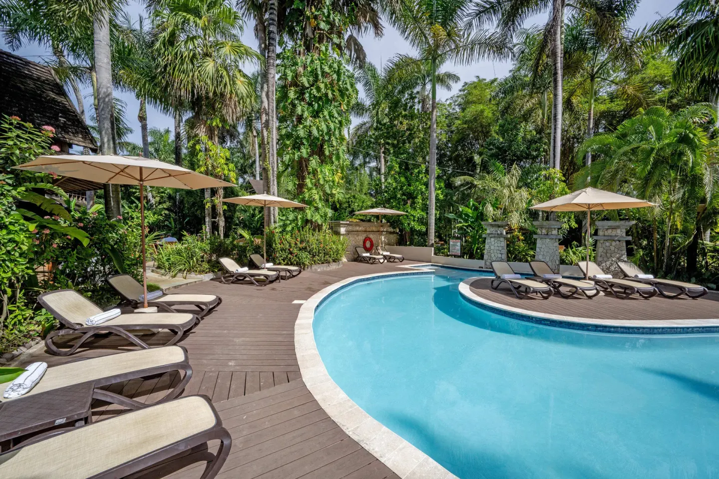 Quiet pool with loungers and umbrellas among palms at Sunset at the Palms Resort.