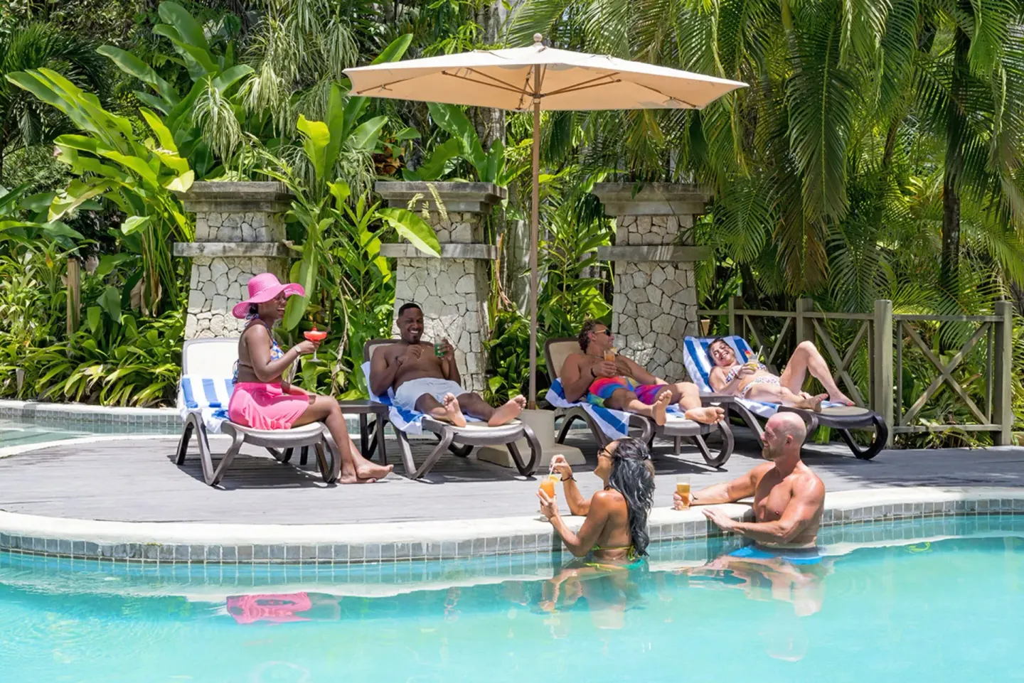 Guests relaxing on loungers and in the pool at Sunset at the Palms Resort.