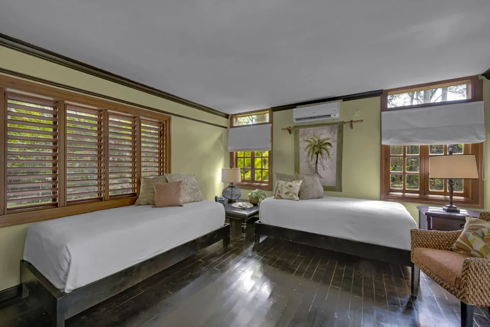 Two beds in a Treetop 1-Bedroom Suite at Sunset at the Palms Resort with shuttered windows.