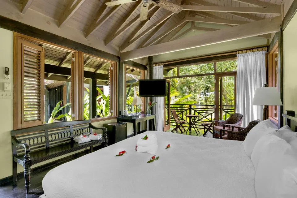 Treetop Deluxe king bed beside balcony doors at Sunset at the Palms Resort.