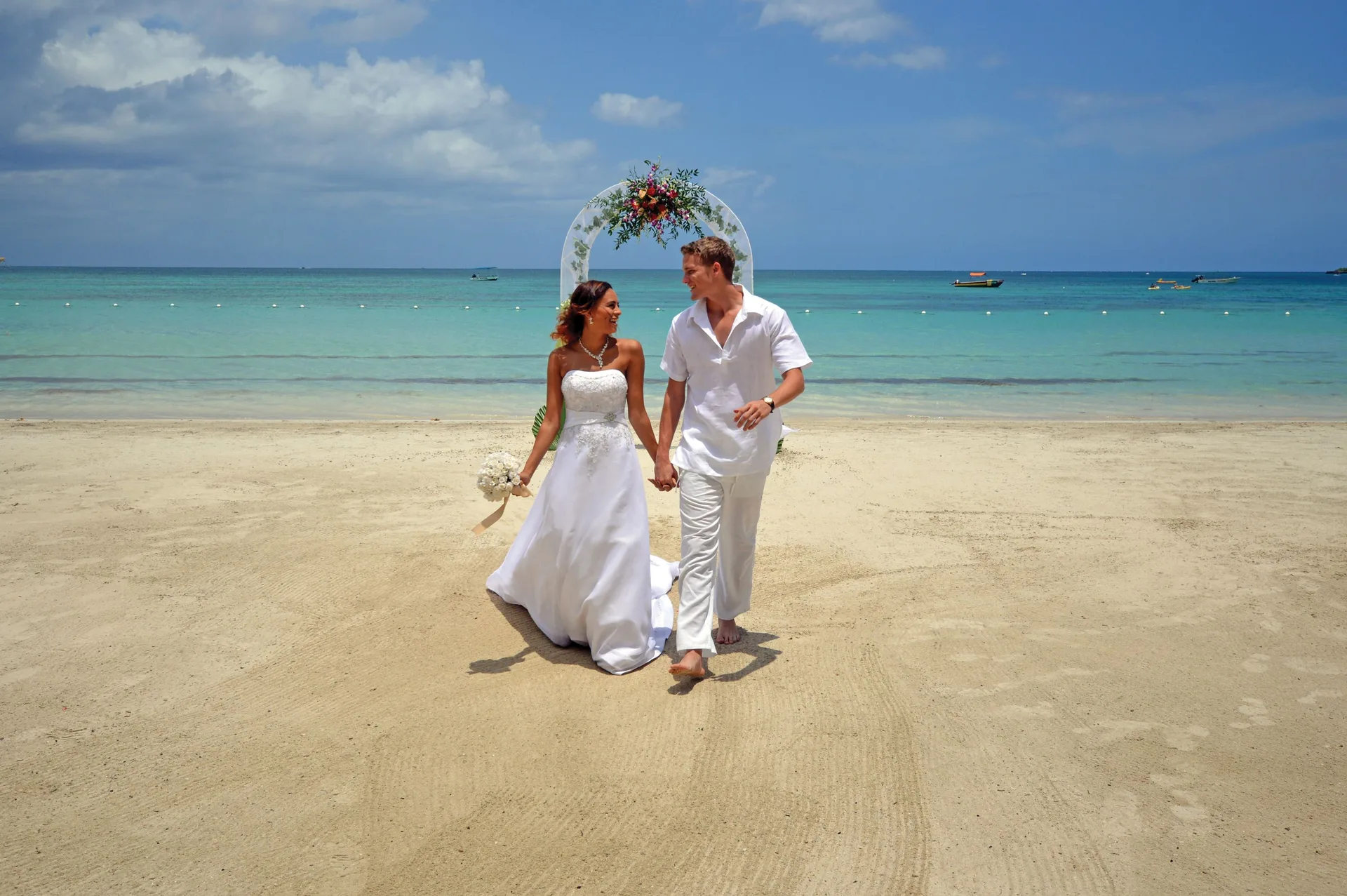 Bride and groom walking on the beach at Sunset at the Palms Resort.