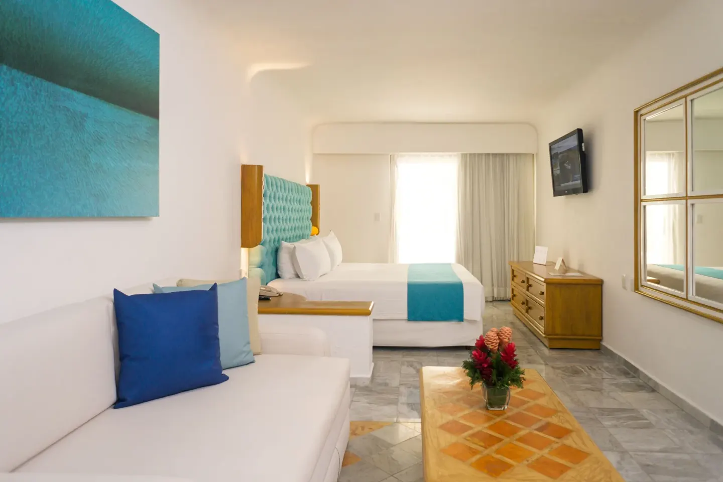 Guest room with king bed, sofa, and turquoise accents at Sunset Marina Resort & Yacht Club.