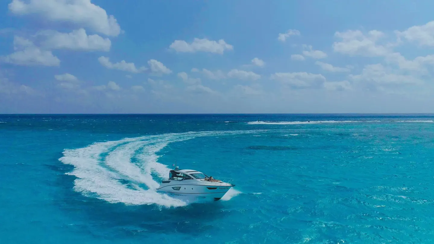 A motor yacht turns through turquoise water near Sunset Marina Resort & Yacht Club.