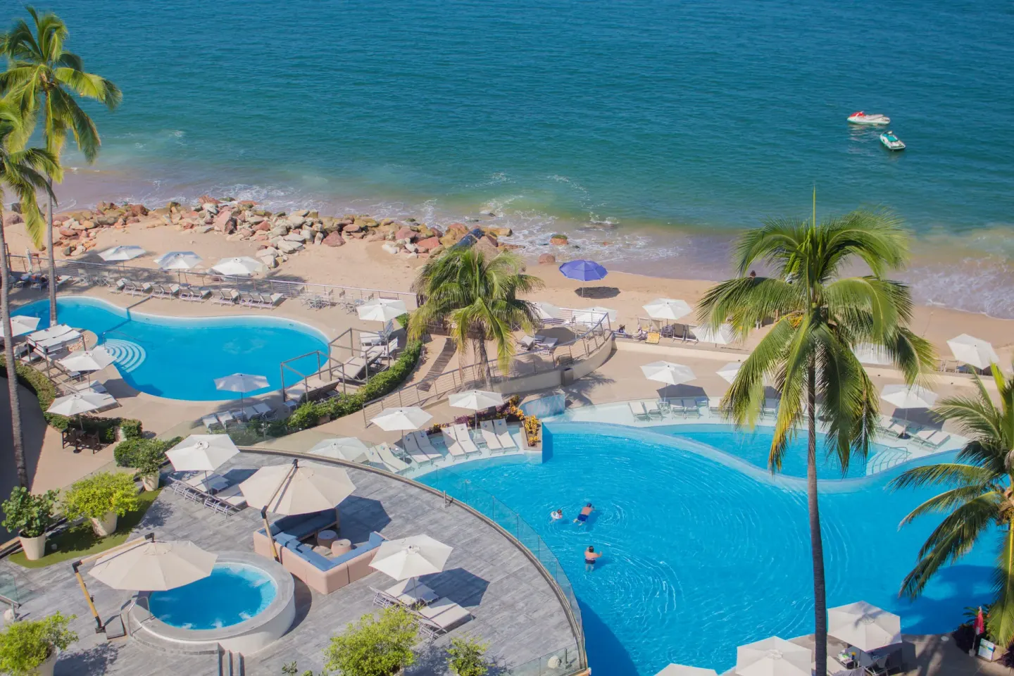 Aerial view of pools, beach loungers, palms, and ocean at Sunset Plaza Beach Resort & Spa Pto Vallarta.