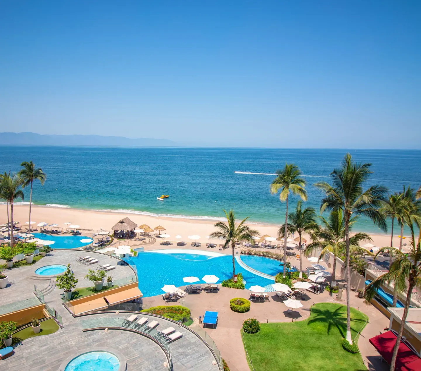 Beach, pools, palms, and blue ocean at Sunset Plaza Beach Resort & Spa Pto Vallarta.