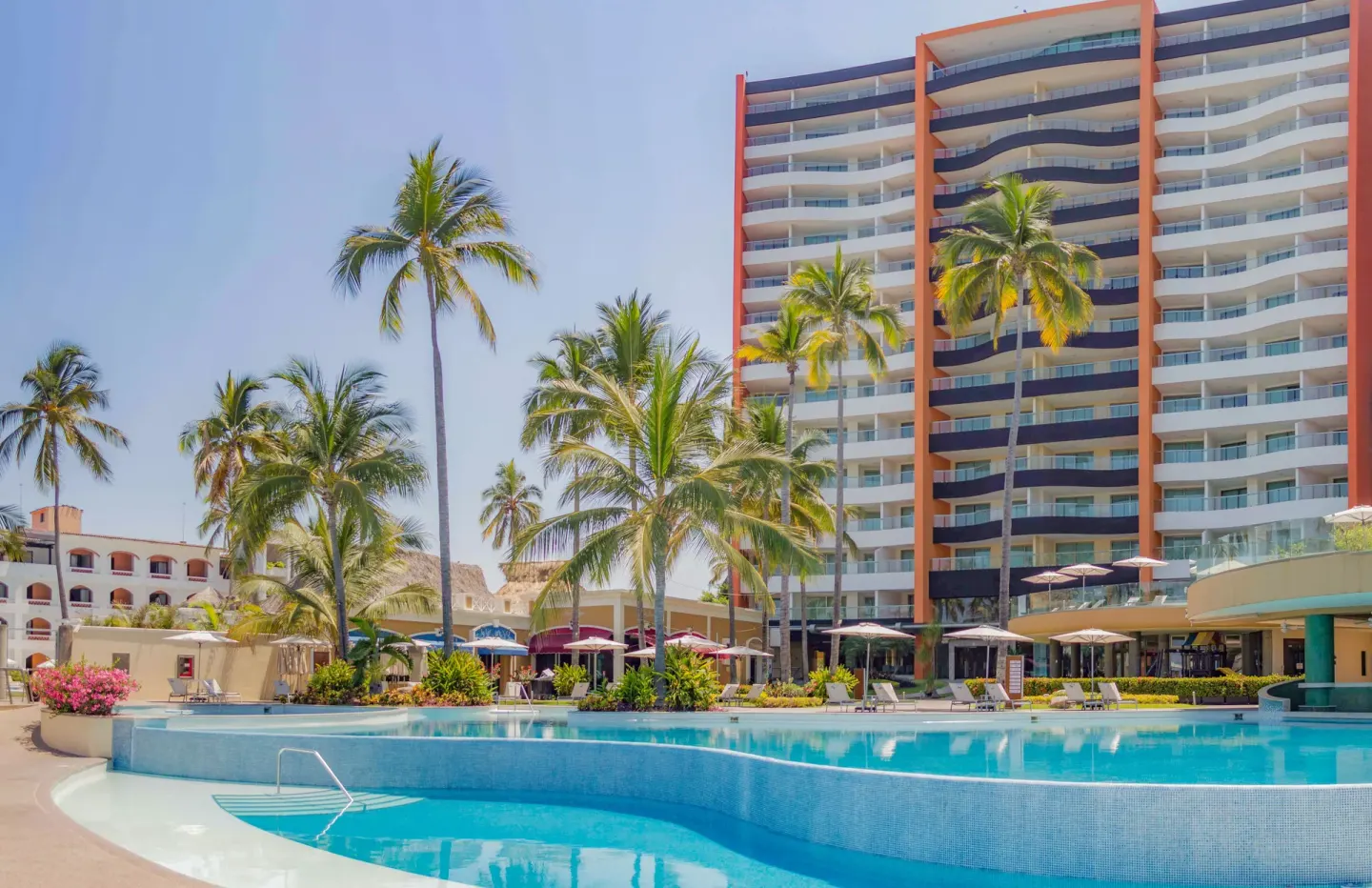 Main pool, palms, umbrellas, and resort tower at Sunset Plaza Beach Resort & Spa Pto Vallarta.