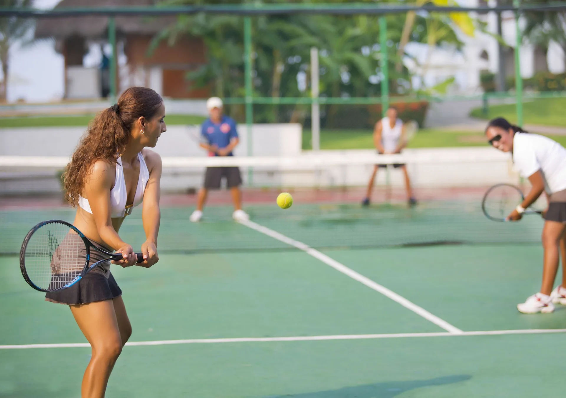 Guests playing tennis on an outdoor court at Sunset Plaza Beach Resort & Spa Pto Vallarta.