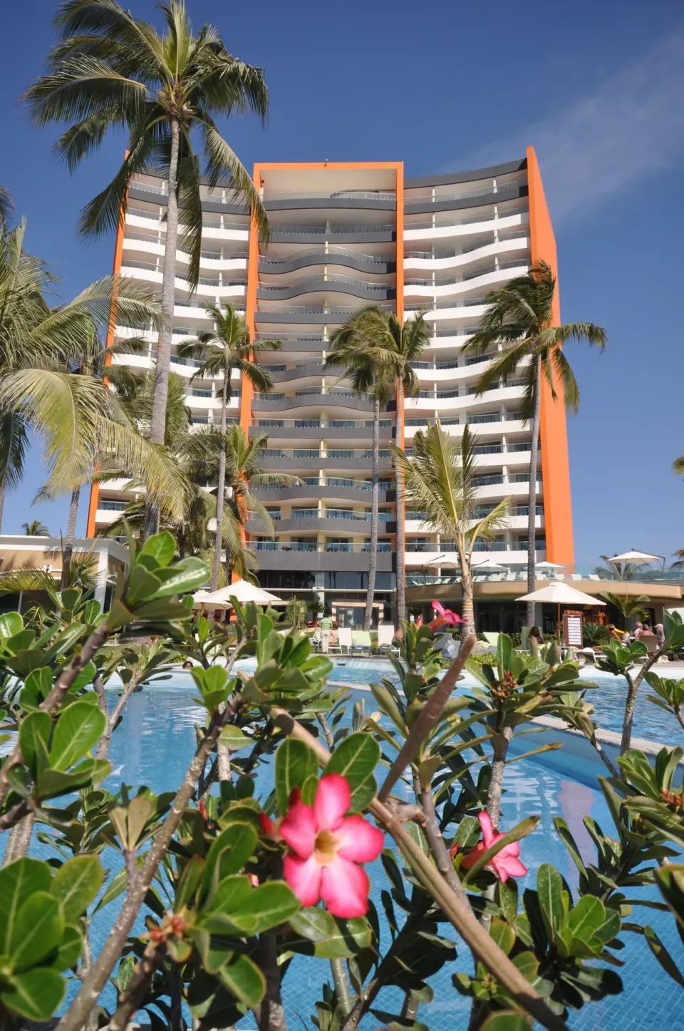 Pool, palms, and tower exterior at Sunset Plaza Beach Resort & Spa Pto Vallarta.