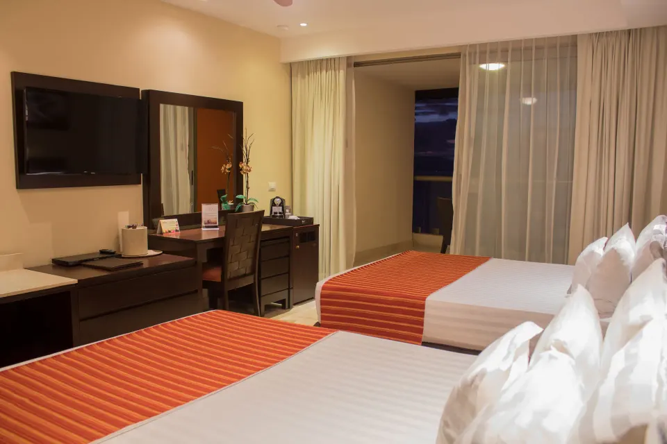 Deluxe Ocean Front room with two beds and desk at Sunset Plaza Beach Resort & Spa Pto Vallarta.
