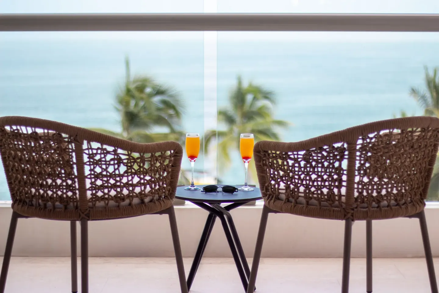 Two woven balcony chairs with drinks overlooking the ocean at Sunset Plaza Beach Resort & Spa Pto Vallarta.
