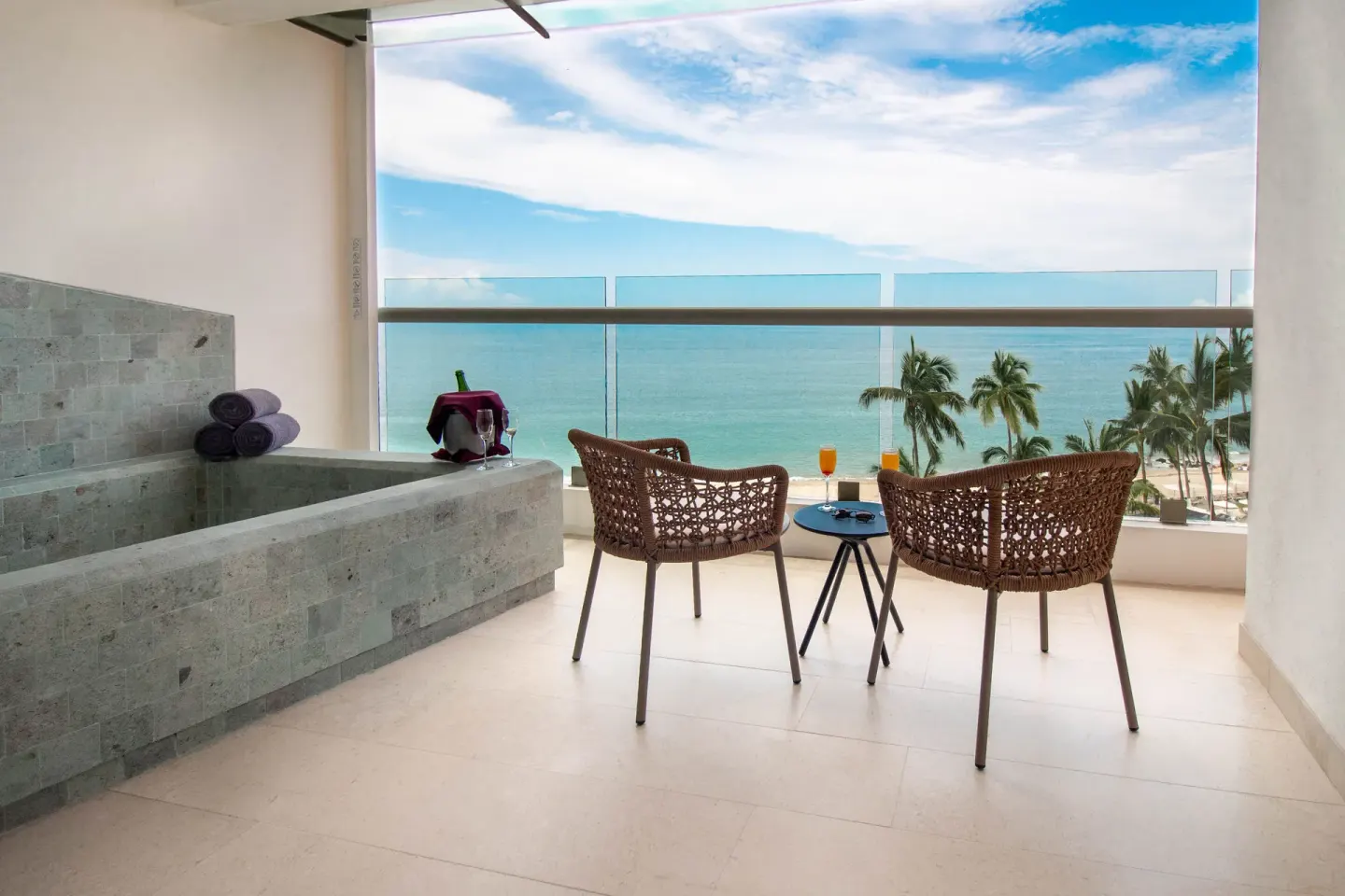 Ocean-front balcony with soaking tub and wicker chairs at Sunset Plaza Beach Resort & Spa Pto Vallarta.