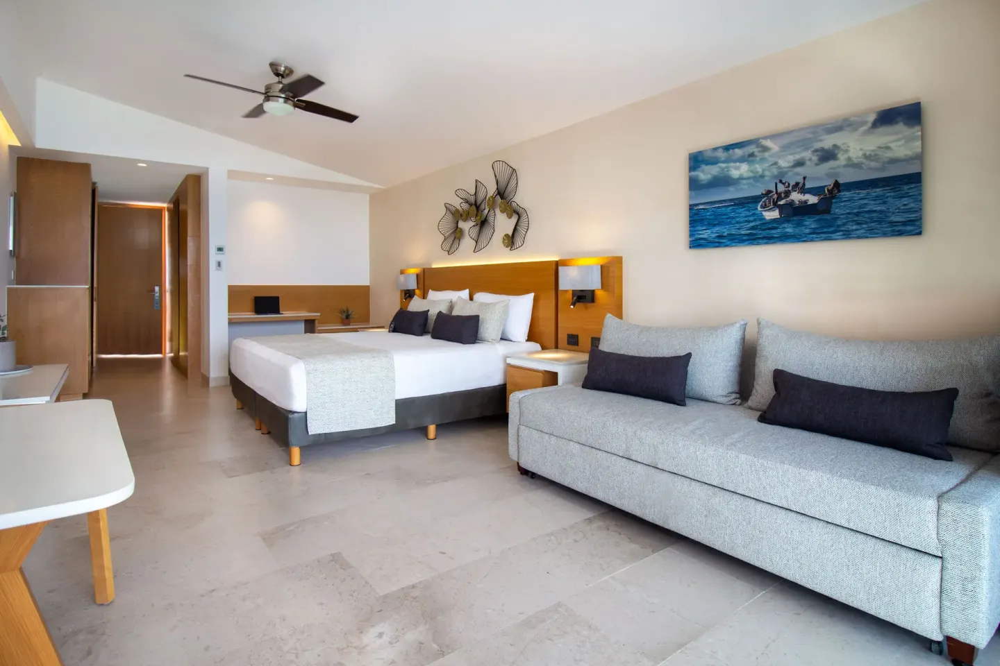 Deluxe Premium Ocean Front room with king bed and gray sofa at Sunset Plaza Beach Resort & Spa Pto Vallarta.