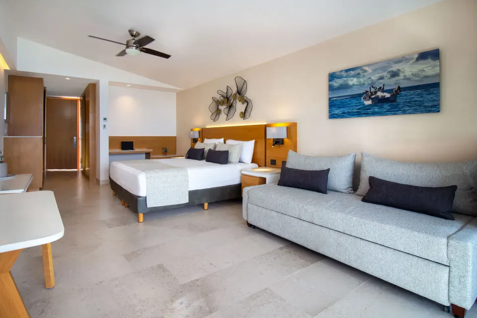 Deluxe Premium Ocean Front room with king bed and gray sofa at Sunset Plaza Beach Resort & Spa Pto Vallarta.